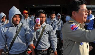 A Cambodian policeman escorts thirty trafficked fishermen returning from Indonesia after being freed or escaping from slave-like conditions on Thai fishing vessels at the Phnom Penh International airport on December 12, 2011. (Tang Chhin Sothy/AFP/Getty Images) Cambodian trafficking victims return home